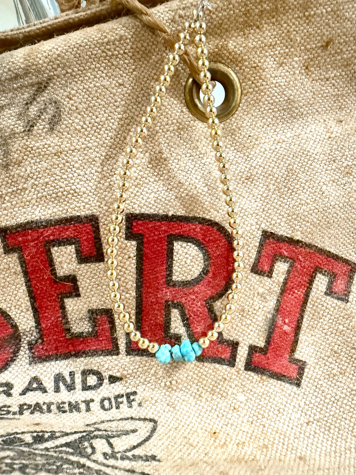 Necklace with turquoise beads on a vintage-style bag with red text