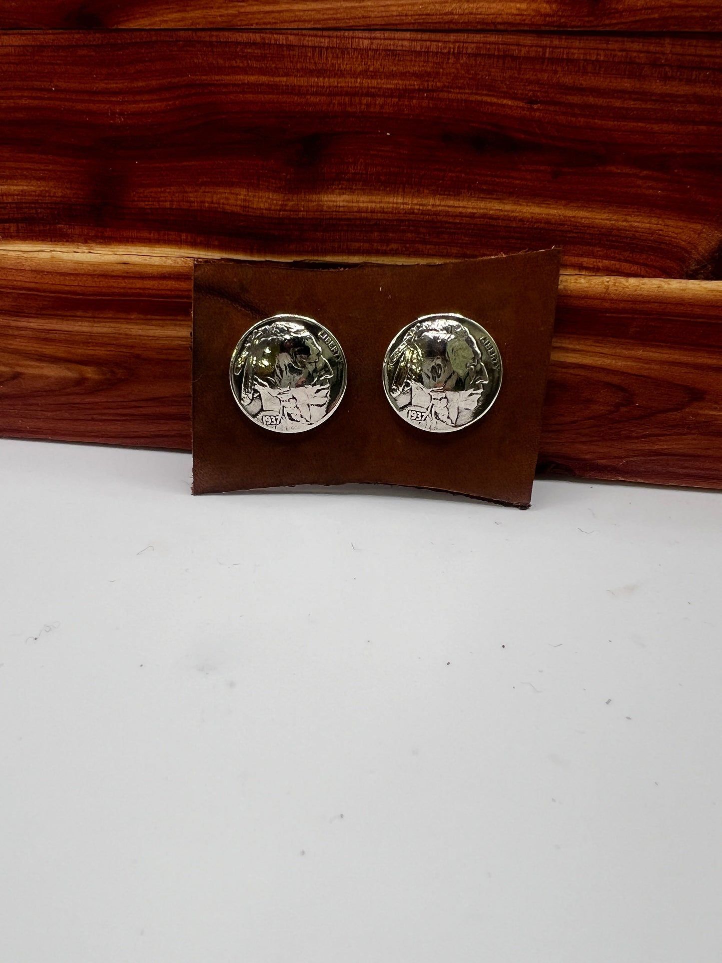 Silver round earrings on a brown rectangular card against a white background