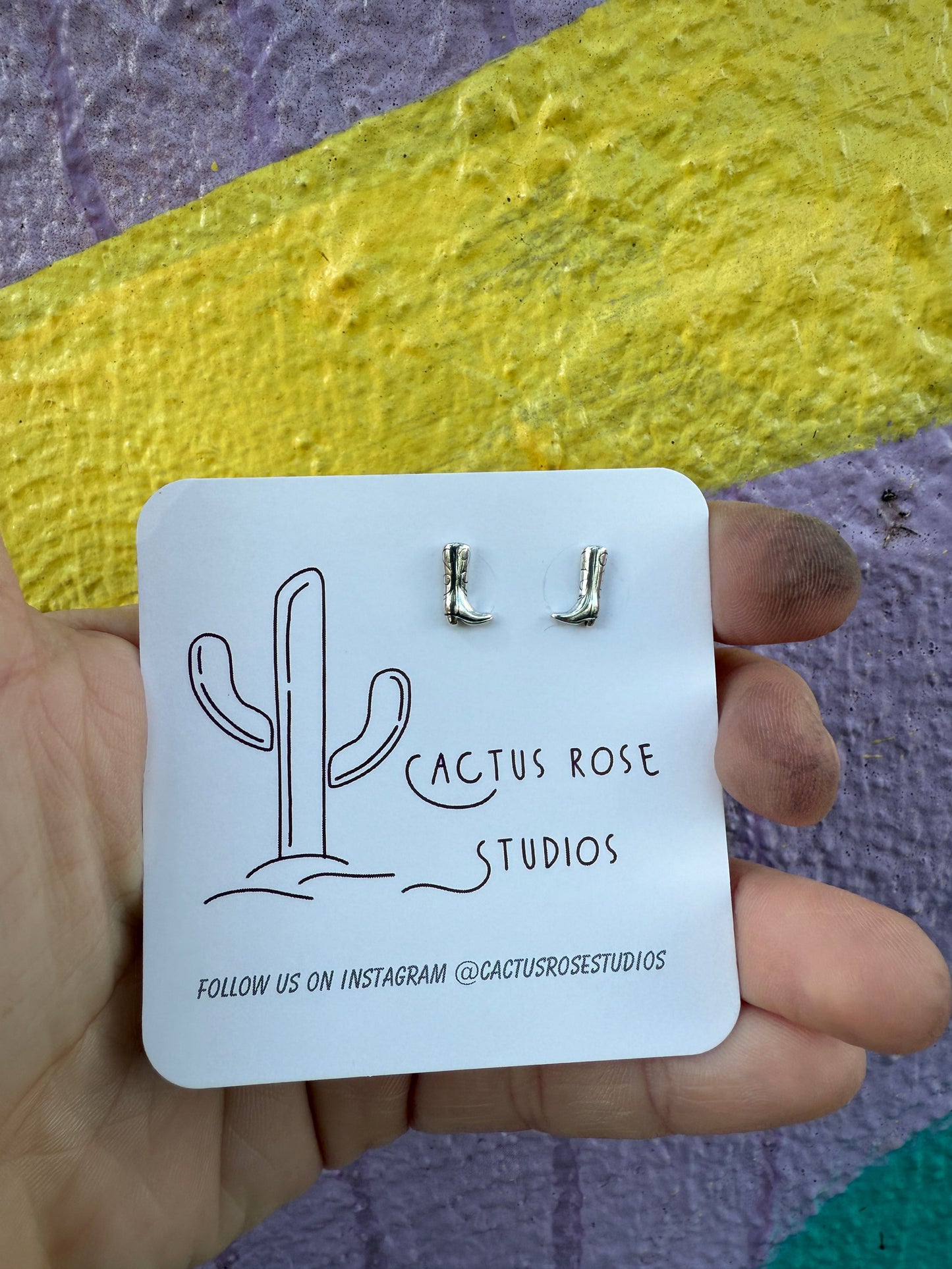 boot shaped earrings against a colorful background