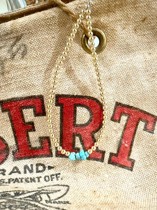 Necklace with turquoise beads on a vintage-style bag with red text