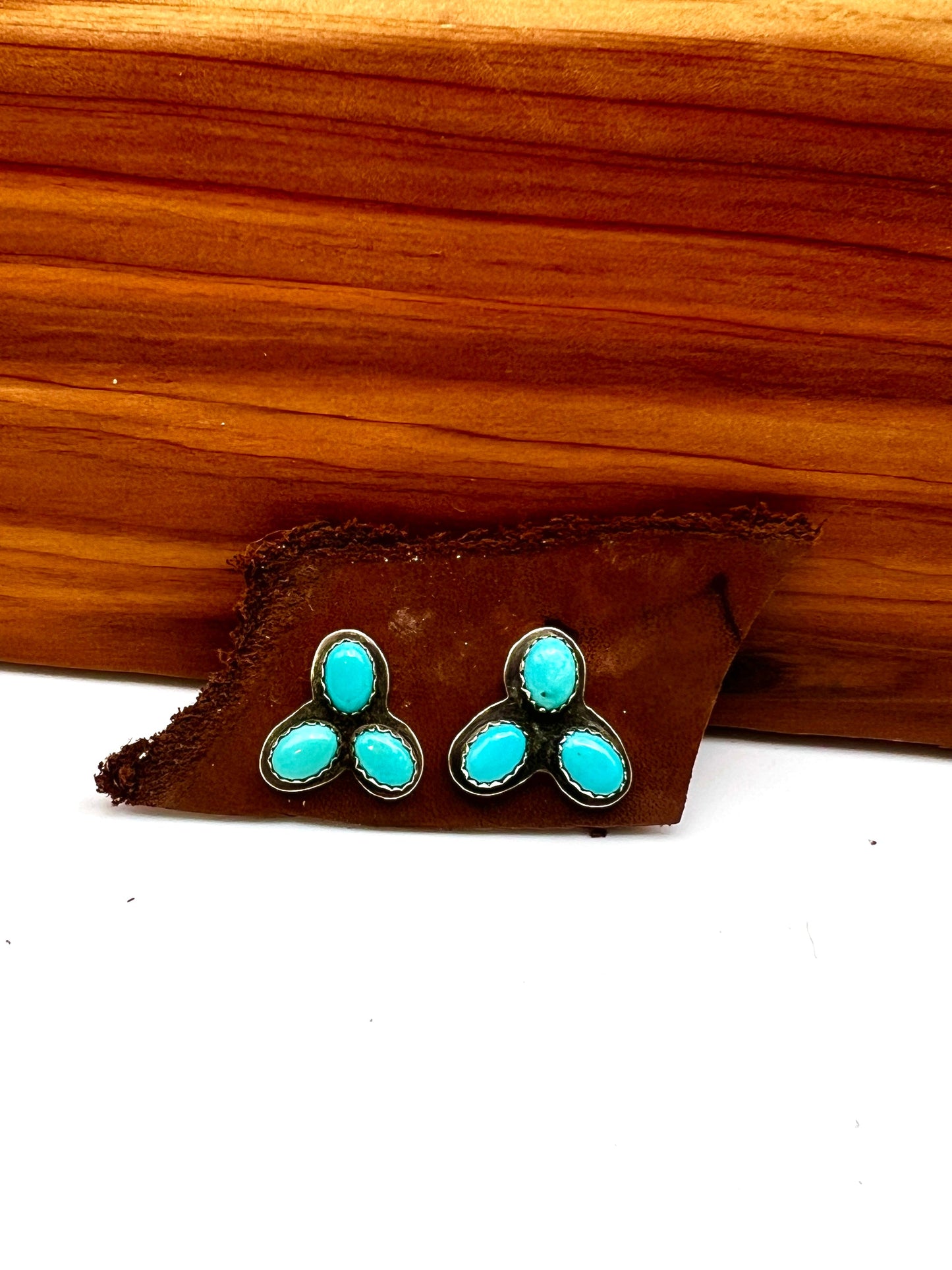 Turquoise stone stud earrings on a wooden stand