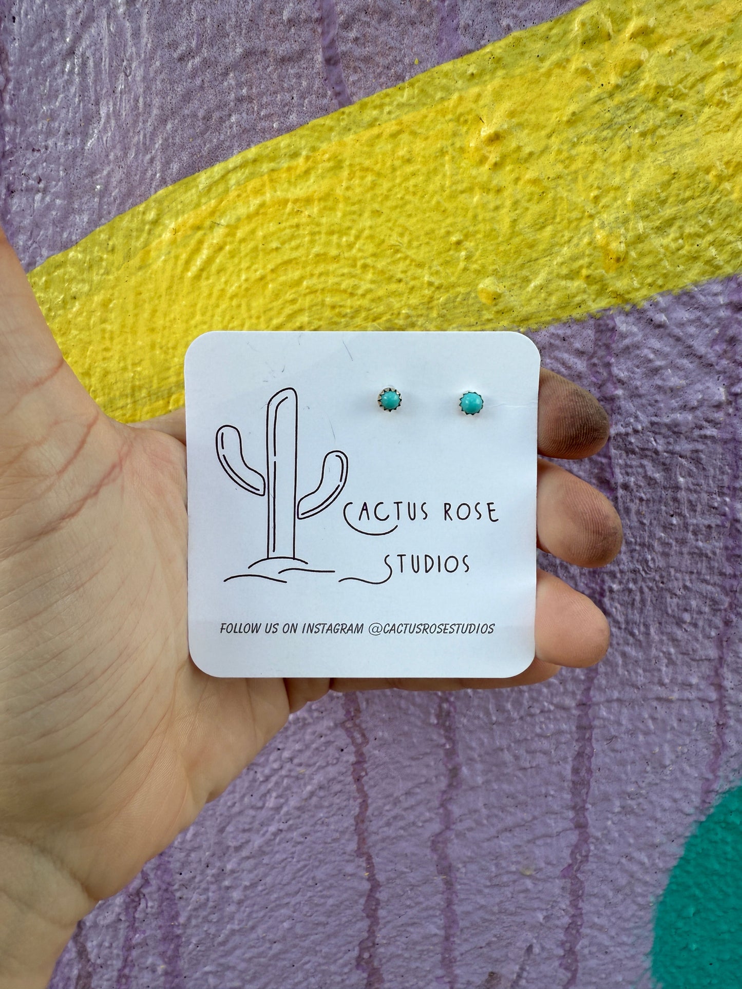 small turquoise earrings against a colorful background