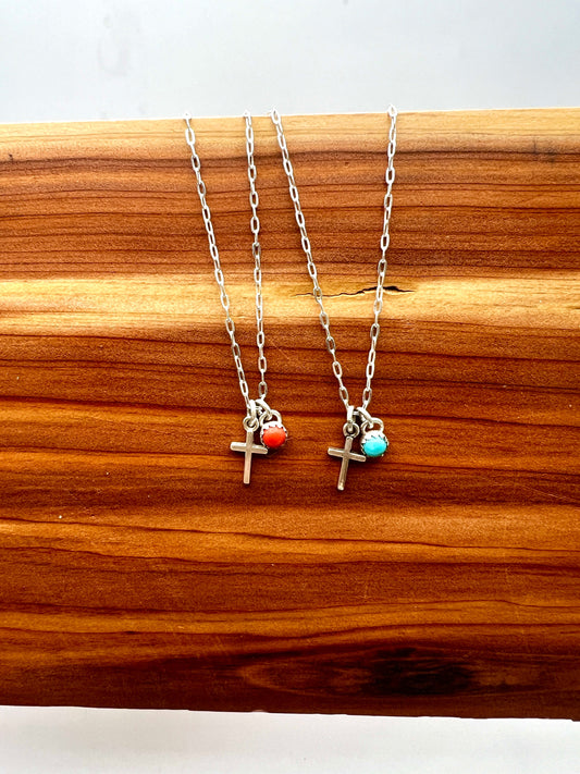Two silver necklaces with cross charms on a wooden surface