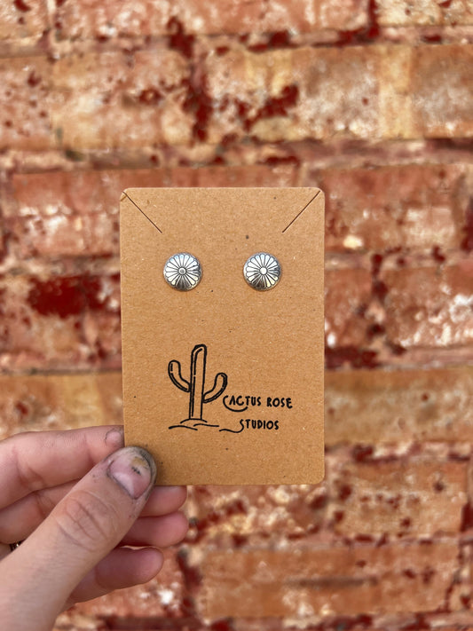 Pair of silver earrings on a Cactus Rose Studios card held against a brick wall.